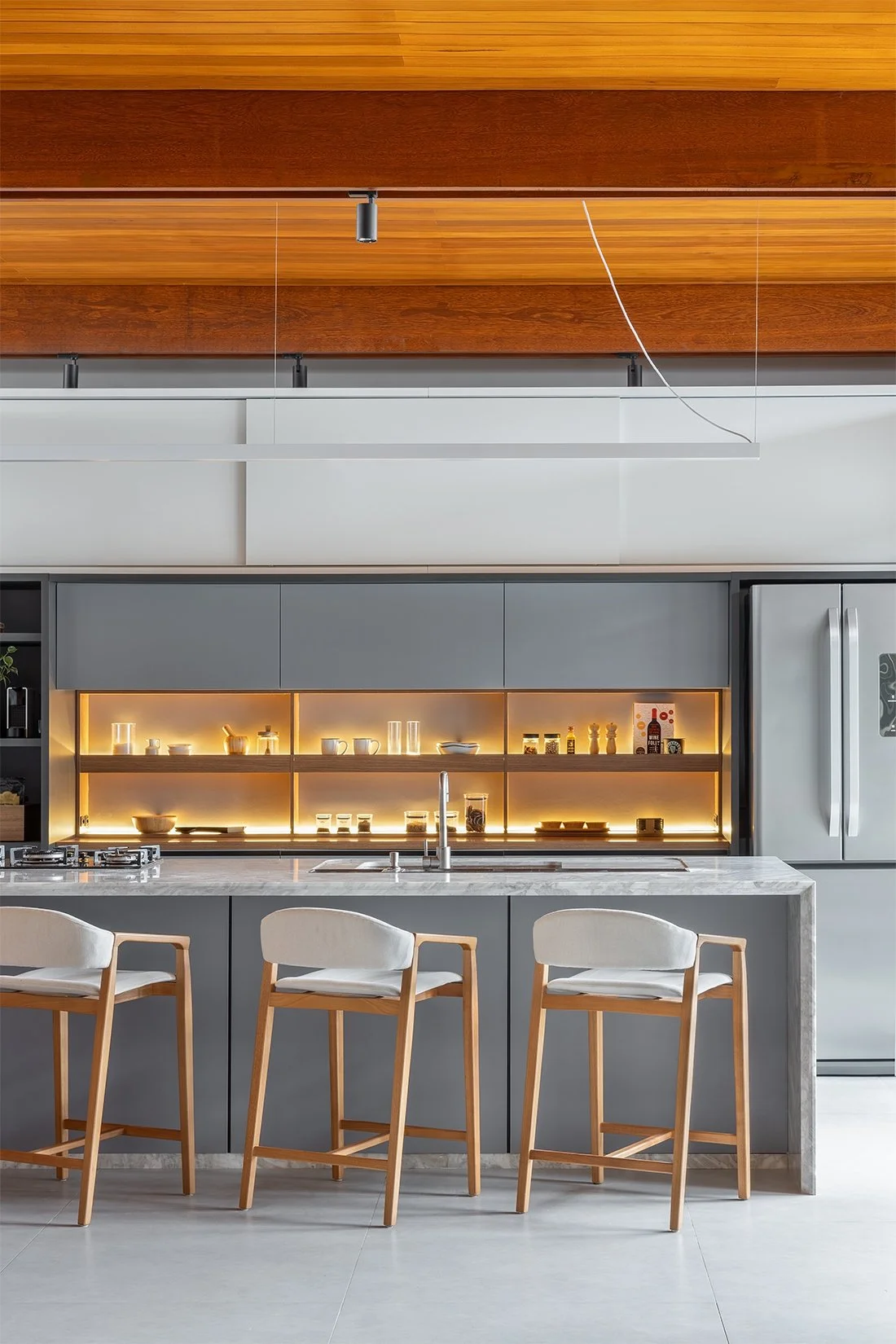 Cozinha com ilha, banquetas e marcenaria iluminada — Casa 88, VK Arquitetos