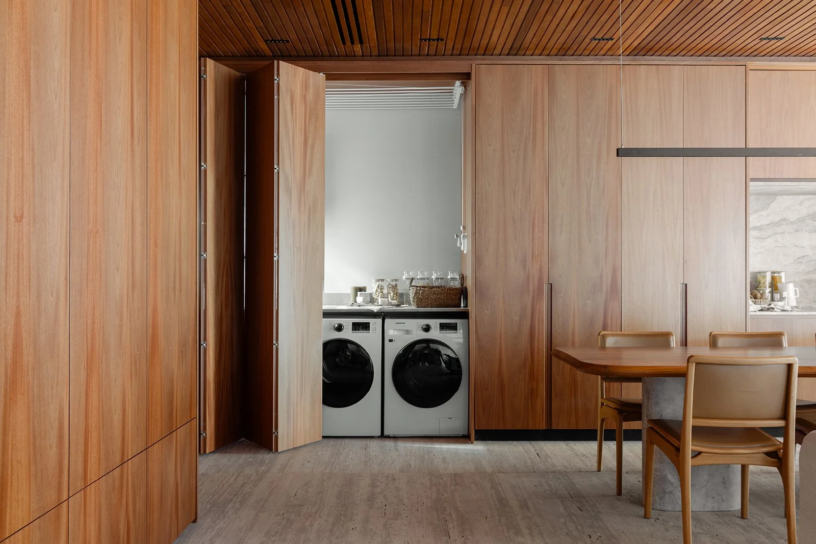 Lavanderia integrada atrás das portas de madeira — Apartamento Jequitibá, VK Arquitetos
