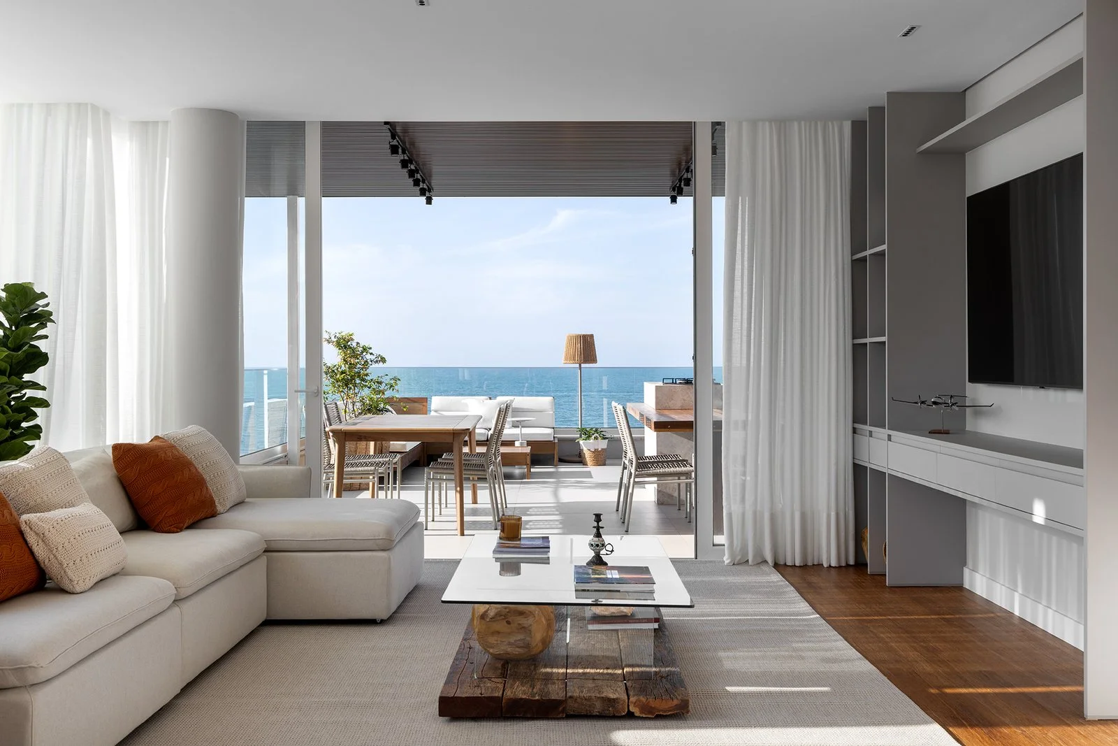 Living integrado com sofá claro e painel de TV — Cobertura Bleu, VK Arquitetos